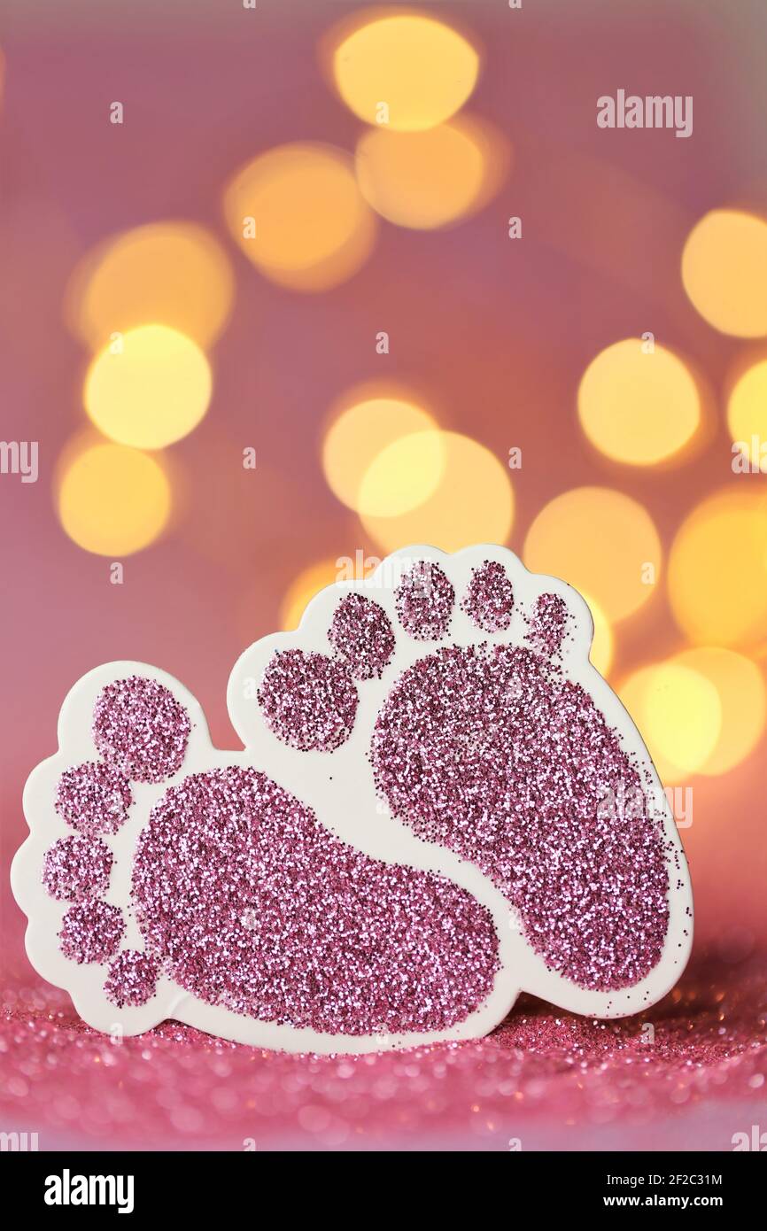 Carte de nouveau-né.la naissance d'une fille. Pieds décoratifs roses scintillants pour bébés sur fond rose pailleté avec bokeh.Baby invitation multicolore jaune Banque D'Images