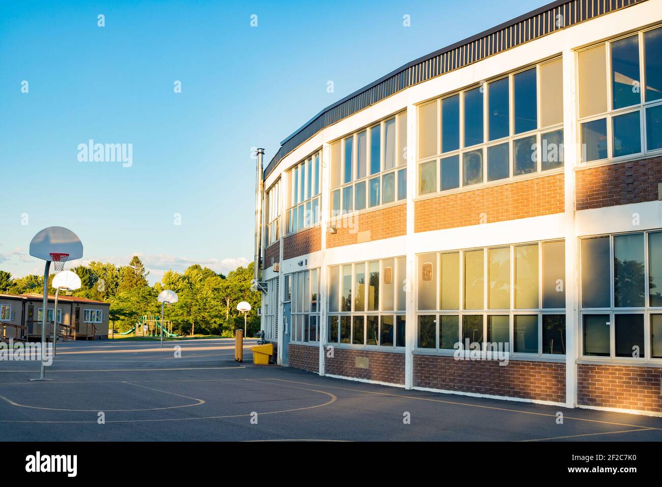 Bâtiment scolaire et cour d'école avec terrain de basket-ball Banque D'Images