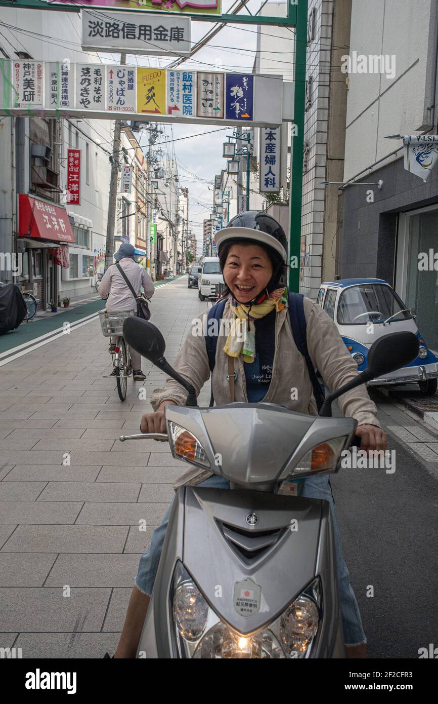 Femme souriante sur scooter à moteur dans la rue , Akashi , préfecture de Hyogo, Japon. Banque D'Images