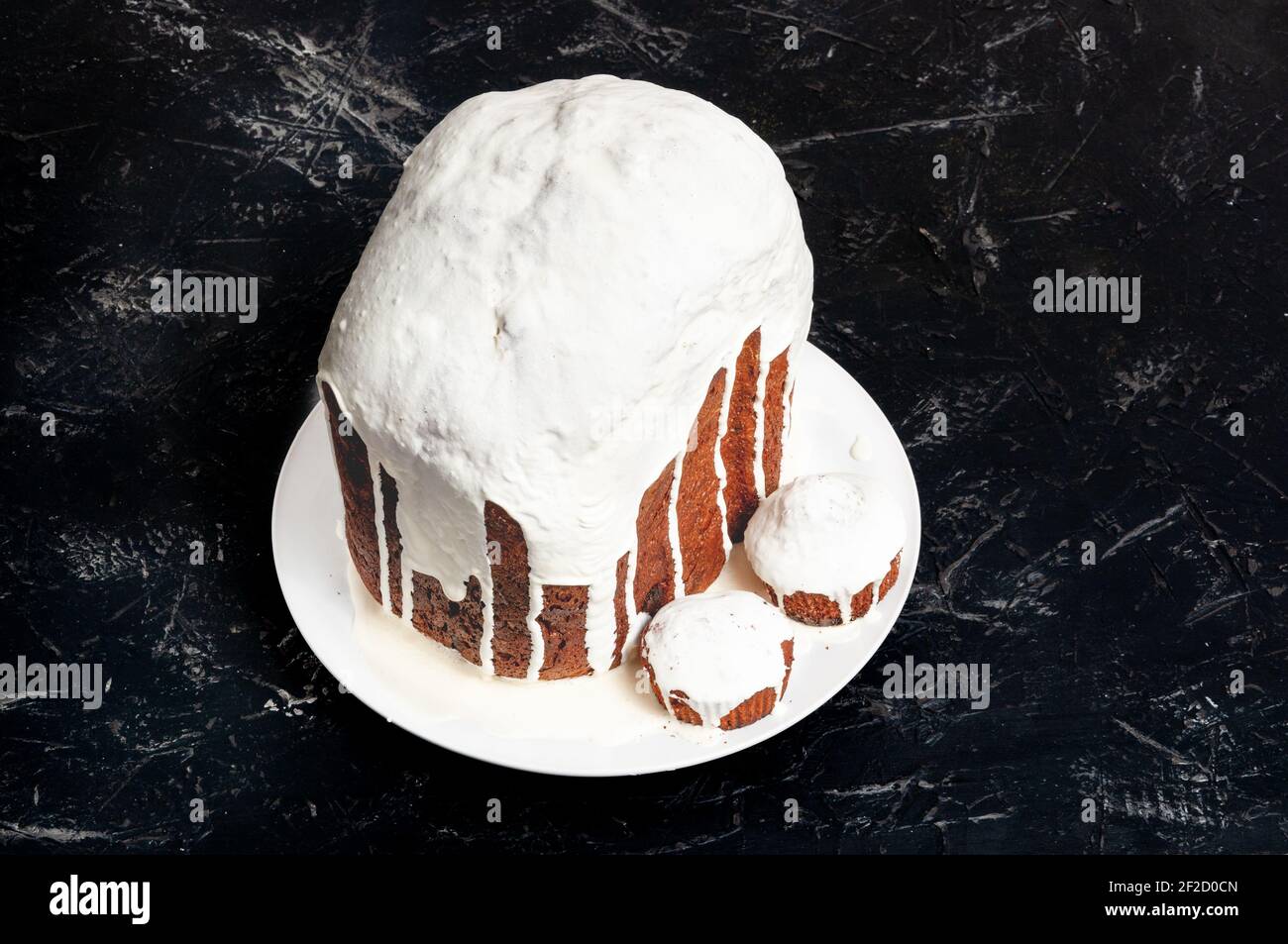 Gâteaux de Pâques artisanaux faits maison, couverts de glaçage blanc, sur une assiette sur fond sombre. Banque D'Images