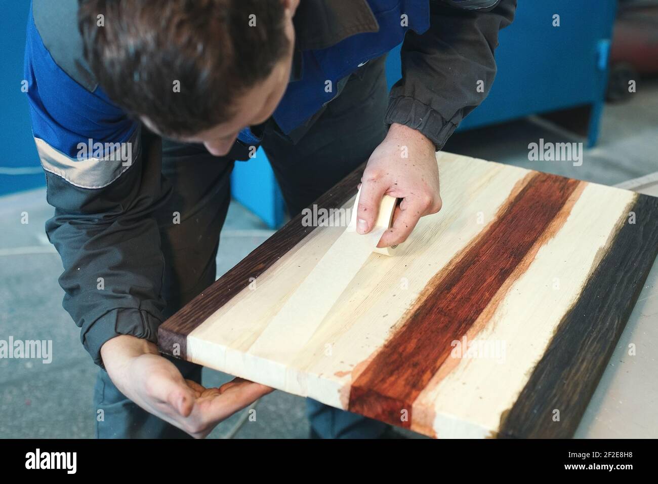 Un ébéniste travaille avec du bois dans un atelier de menuiserie. Un jeune travailleur d'apparence caucasienne fait un comptoir. Banque D'Images