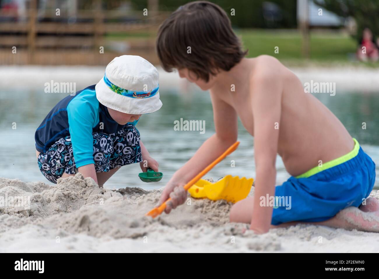 Deux jeunes garçons jouant dans le sable au bord d'un lac. Banque D'Images