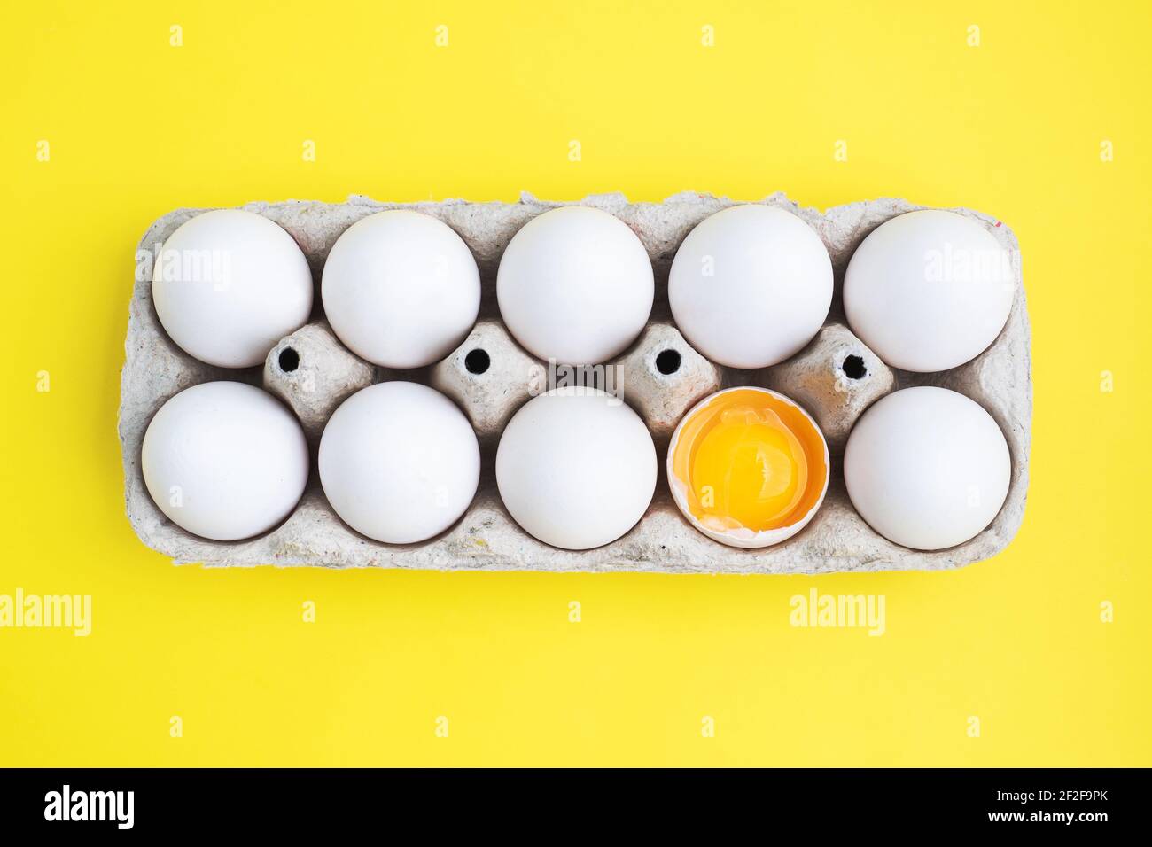 Oeufs de poulet frais dans un paquet, oeufs crus dans une coquille blanche dans une boîte. Espace de copie de la vue de dessus, arrière-plan jaune. Œuf cassé avec jaune Banque D'Images Oeufs de poulet frais dans un paquet, oeufs crus dans une coquille blanche dans une boîte. Espace de copie de la vue de dessus, arrière-plan jaune. Œuf cassé avec jaune Banque D'Images