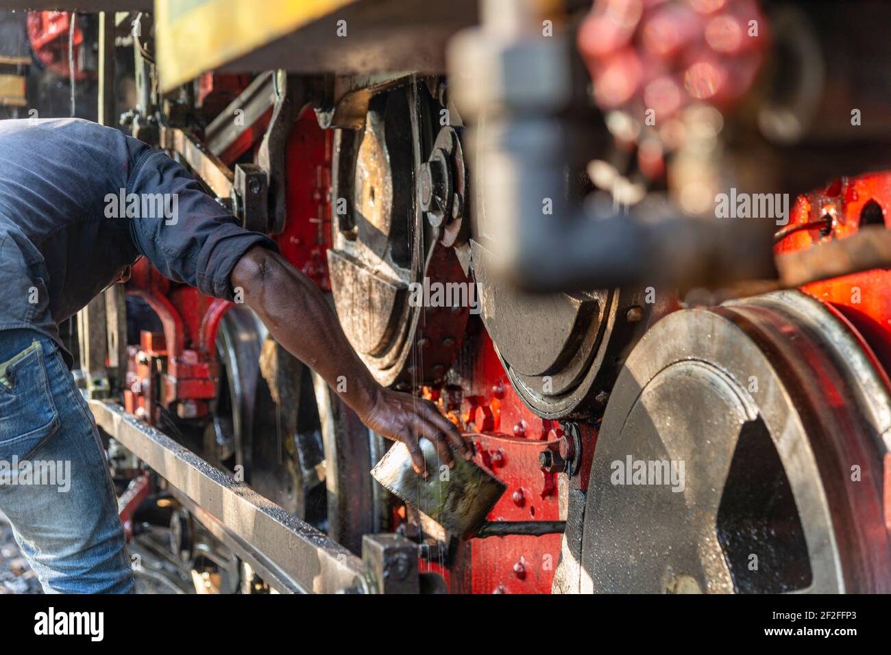 Le conducteur de leurres fait l'huile des roues de la locomotive du train à jouets, Tamil Nadu, Inde Banque D'Images