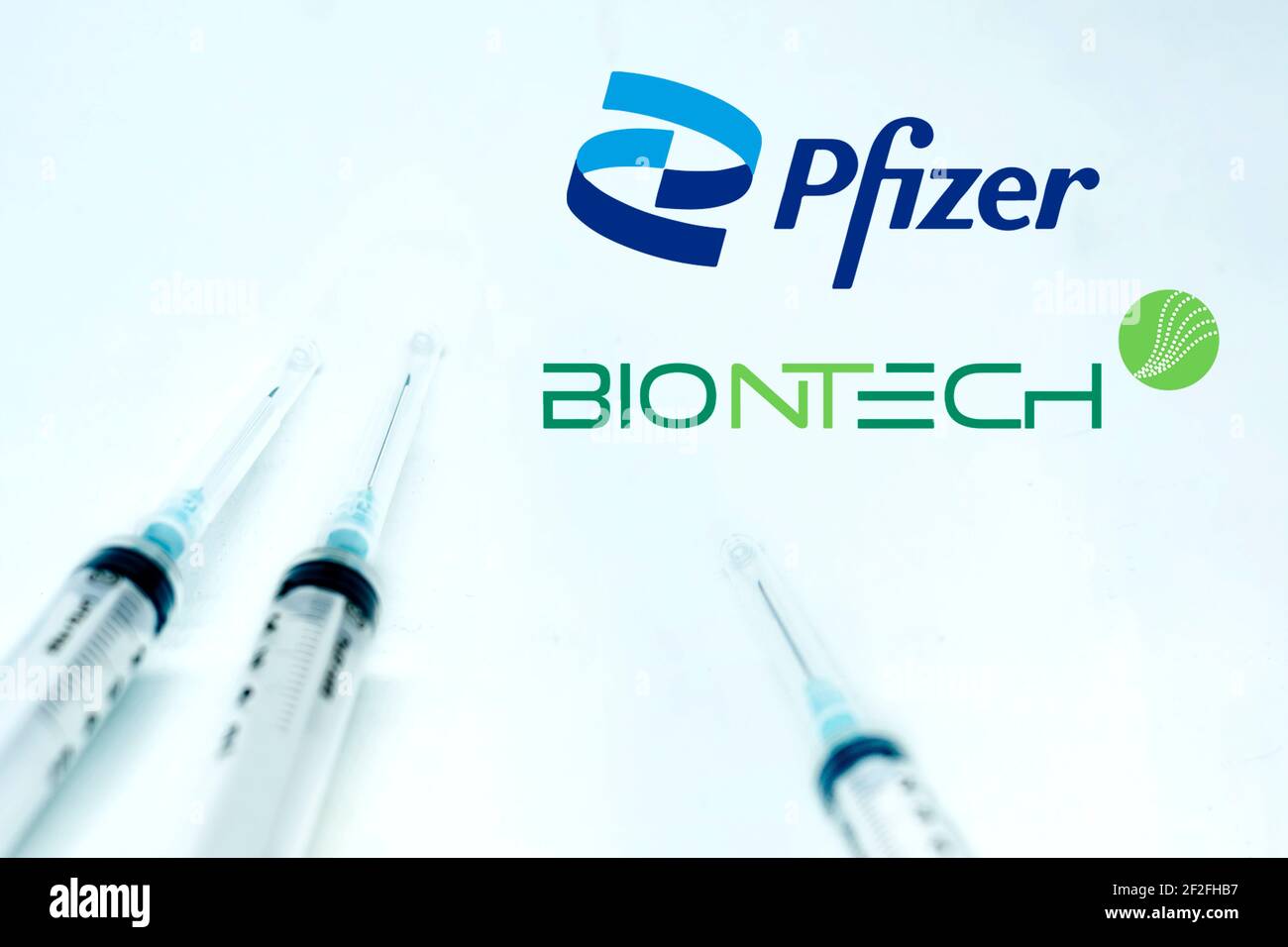 New York USA, 10 février 2021 : trois seringues à côté du logo Pfizer BioNTech isolées sur fond blanc. Santé et prévention.Pfizer Biontech Banque D'Images