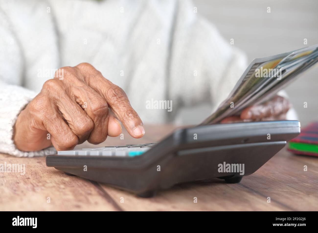 les femmes âgées ont la main à l'aide de la calculatrice et tiennent de l'argent sur la table Banque D'Images