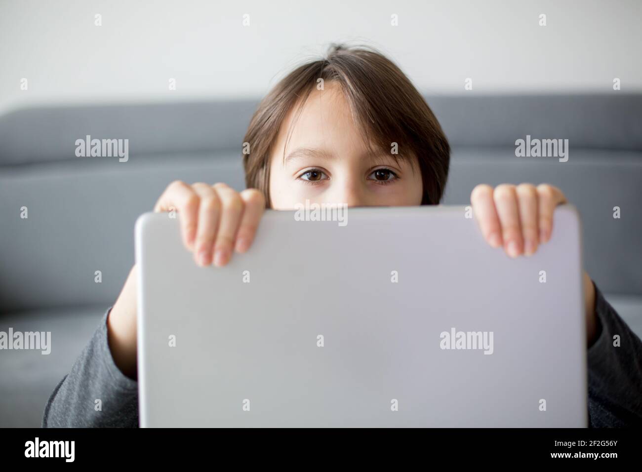 Préadolescents, se cachant derrière le bloc-notes, l'éducation en ligne, les jeux et le plaisir pour les enfants, l'ordinateur comme mauvaise influence pour les enfants Banque D'Images