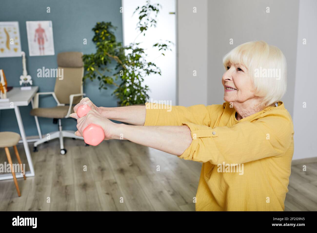 Une femme âgée lève un haltères, elle fait un exercice de traitement au centre de réadaptation Banque D'Images