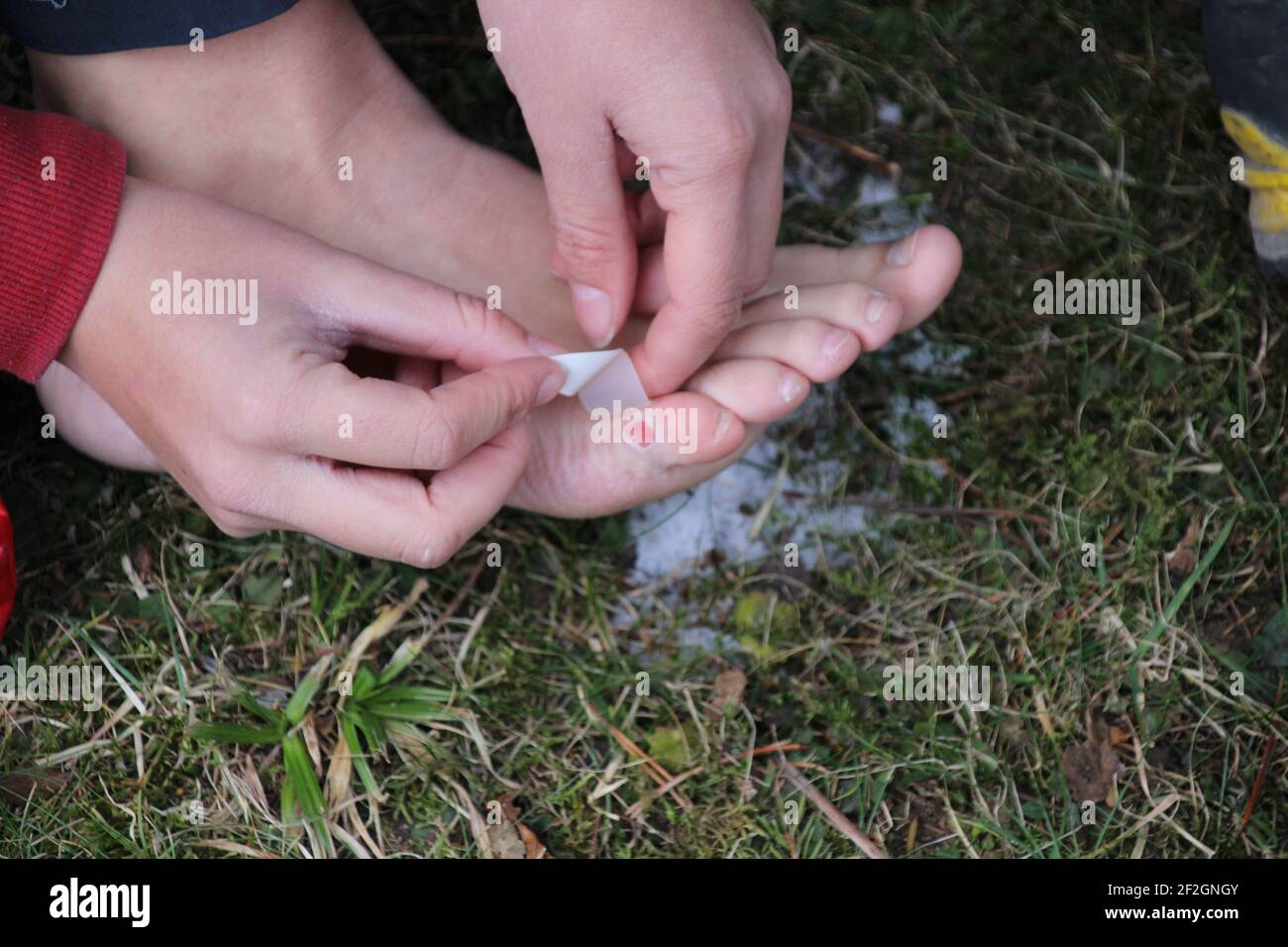 Femme traite la plaquette sur le pied pendant une randonnée, le soin des plaies, les premiers soins, l'urgence, le plâtre, neige Banque D'Images