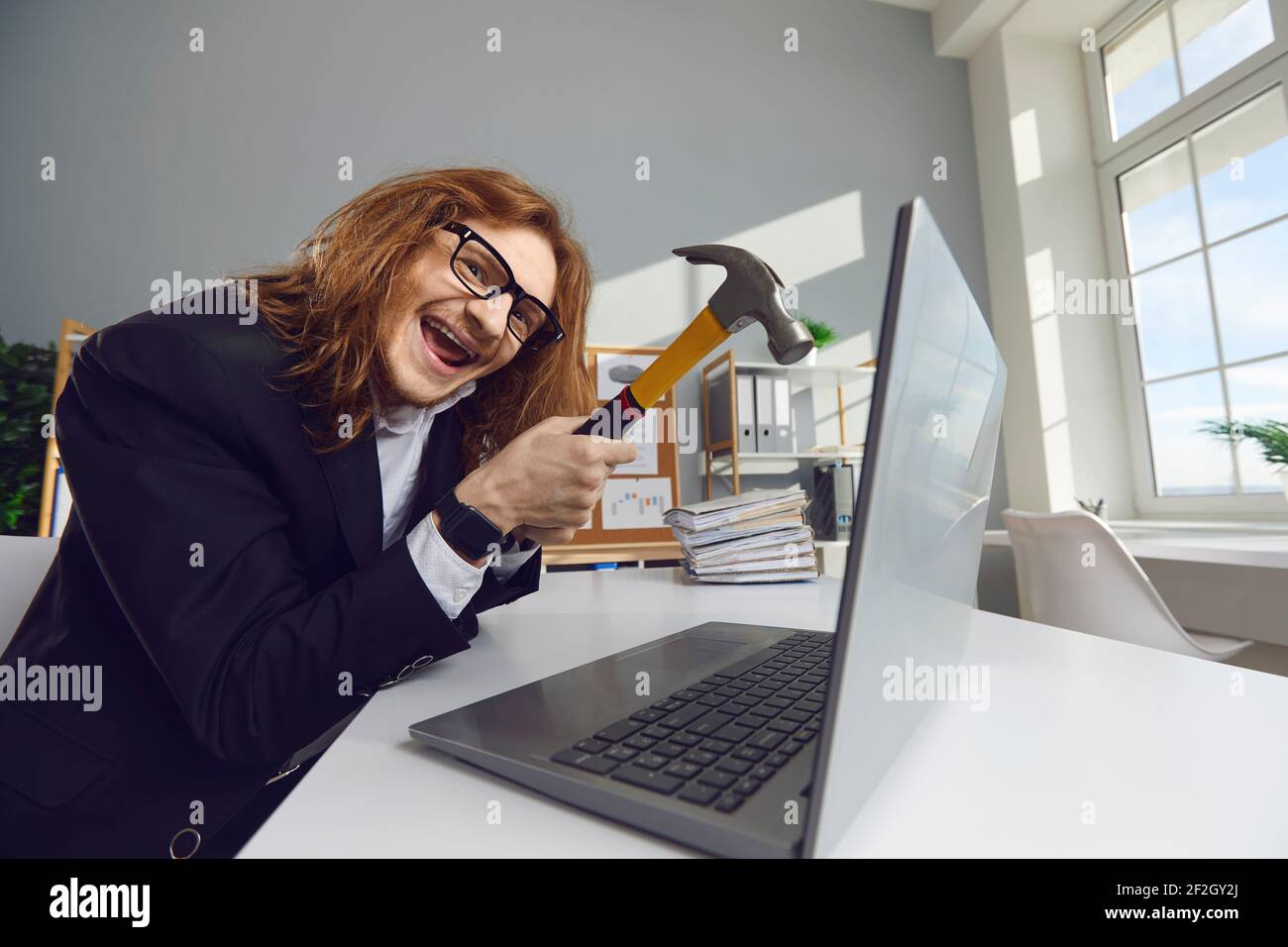 Un travailleur de bureau fou veut se débarrasser de son ordinateur portable et de le frapper avec un marteau Banque D'Images