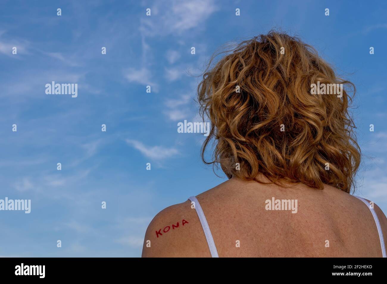 La femme blonde s'est retournée avec le mot 'Kona' qui signifie en islandais une femme sur une épaule, contre un beau ciel bleu avec des nuages blancs Banque D'Images