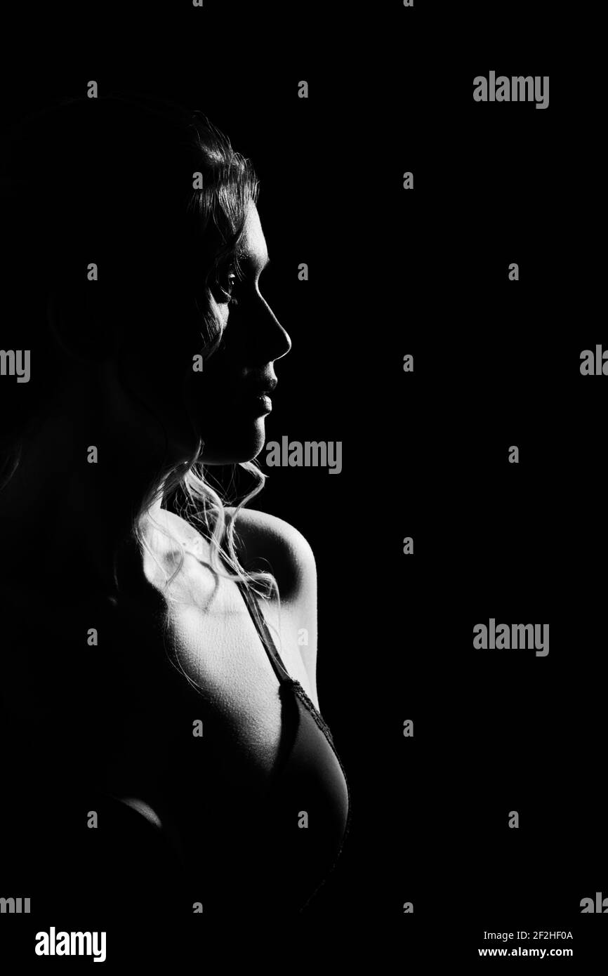 jeune femme sérieuse sur fond noir regardant loin profil latéral affichage monochrome Banque D'Images