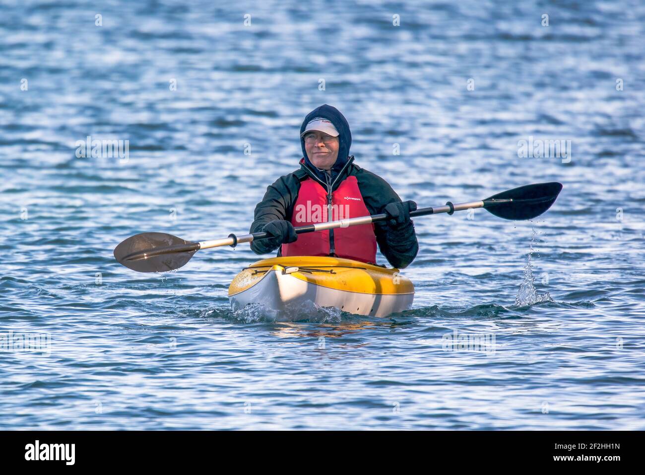 Un homme dans un kayak en profitant d'une très petite saison pagayer le long du canal de Sturgeon Bay Shipping situé dans le comté de Door Wi. Un exemple d'équipement de sécurité approprié Banque D'Images