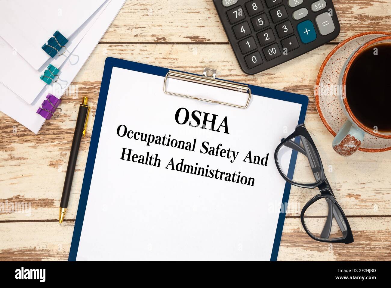 Papier avec texte OSHA - Administration de la sécurité et de la santé au travail sur la table de bureau, la calculatrice et la tasse de café Banque D'Images