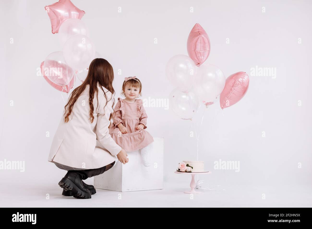 L Anniversaire 2 Ans Petite Fille En Robe Rose Avec Maman Gateau Blanc Creme Avec Roses Decorations D Anniversaire Avec Ballons Blancs Et Roses Et Photo Stock Alamy
