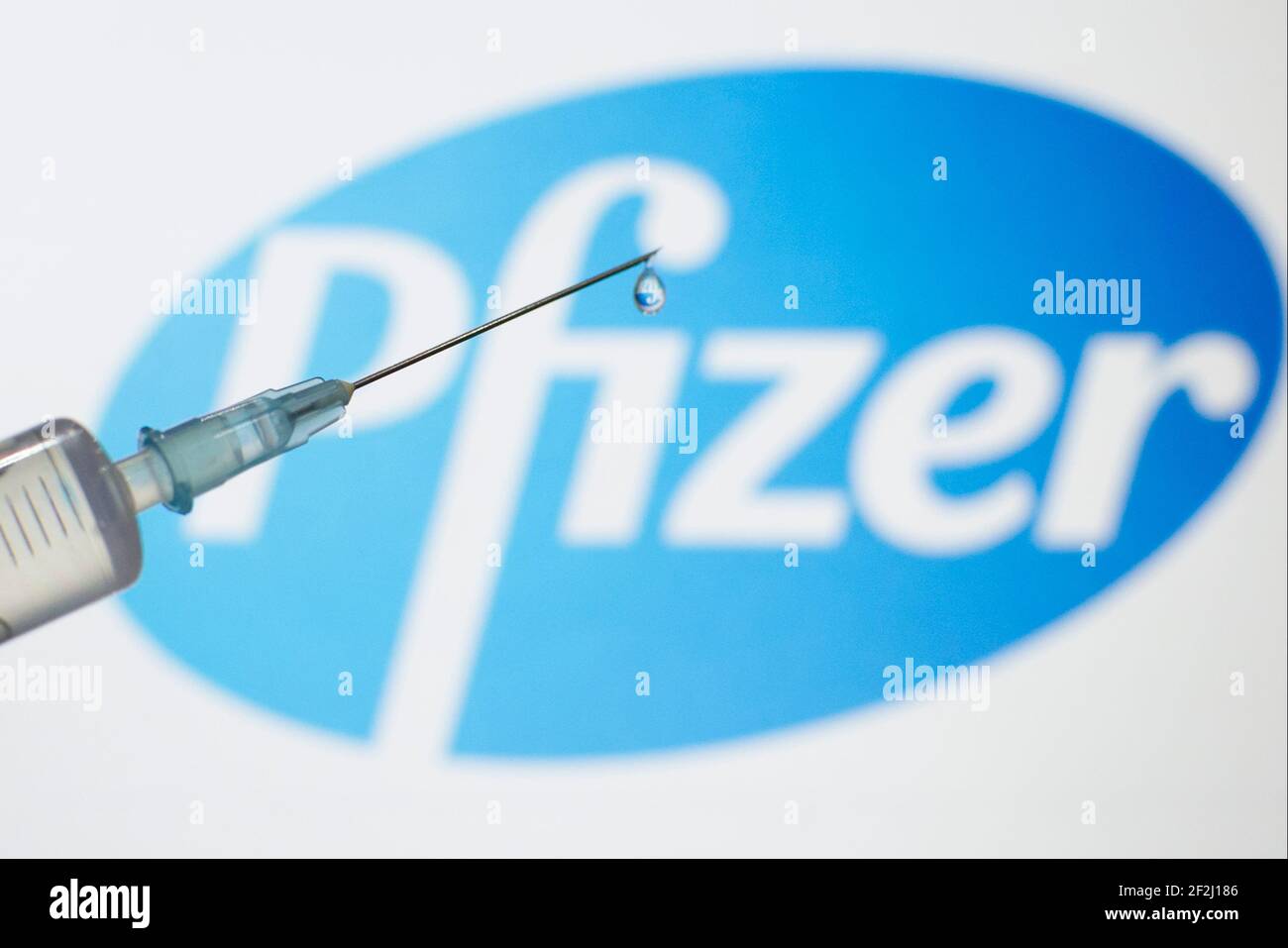 Photographie d'une seringue médicale avec une goutte sortant de l'aiguille,  avec le logo de la compagnie de vaccins du coronavirus Pfizer affiché sur  un bac lumineux Photo Stock - Alamy