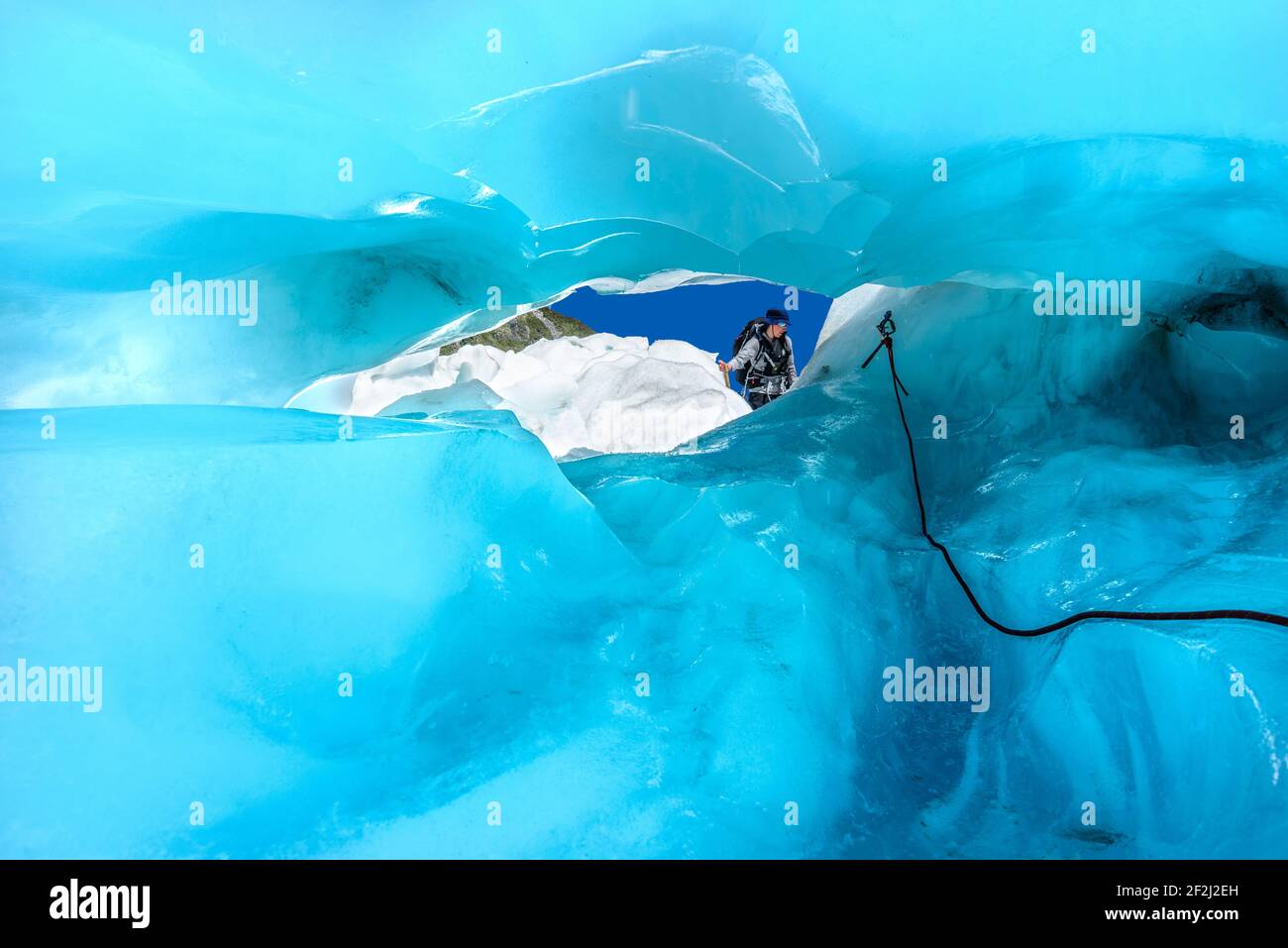 Vue à travers le tunnel de glace bleu sur le grimpeur explorant la beauté de Fox Glacier, South Island, Nouvelle-Zélande. Adrénaline et aventure concept. Banque D'Images