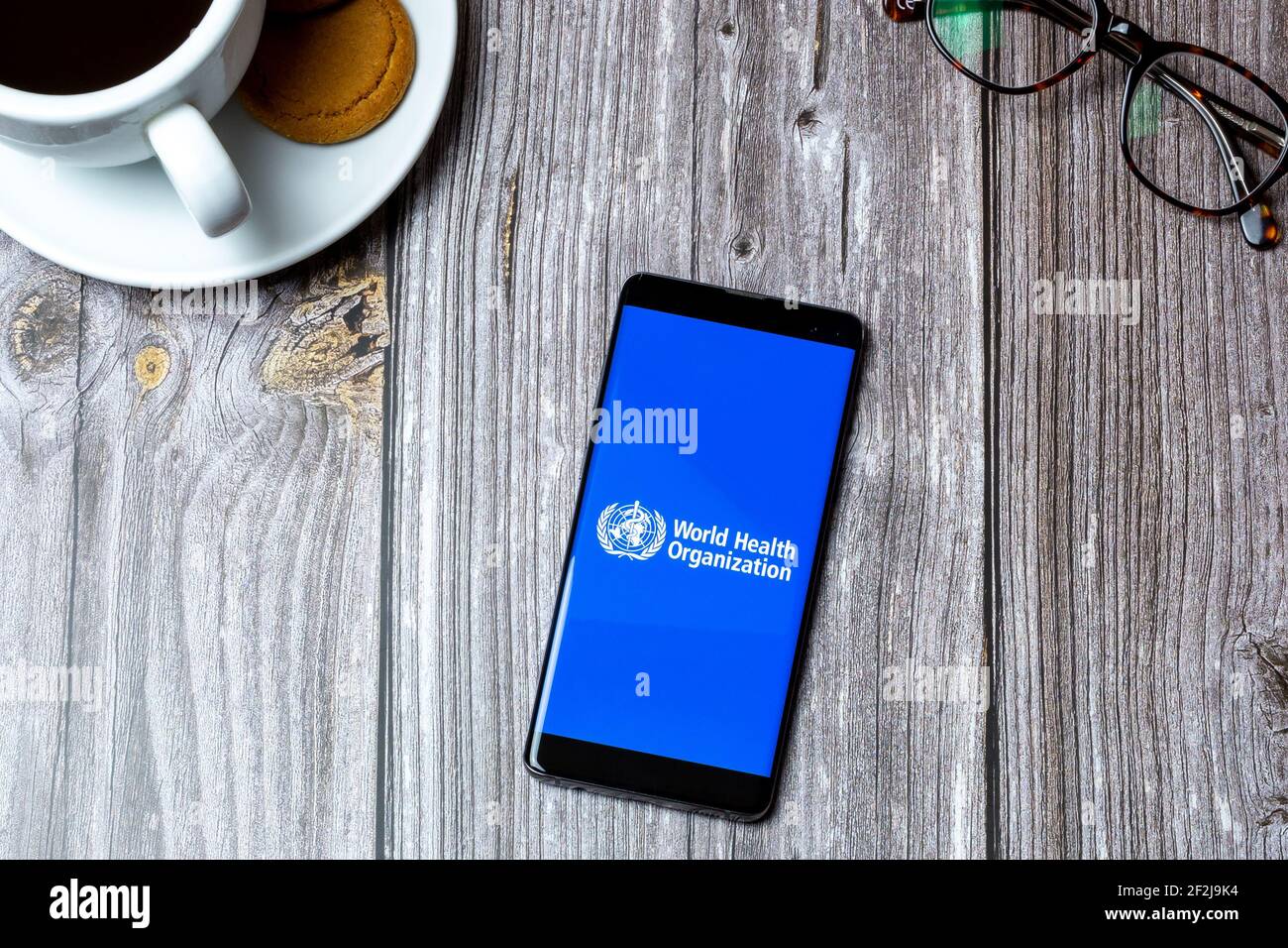 Un téléphone portable ou mobile posé sur un bois Avec l'application de l'Organisation mondiale de la santé ouverte à l'écran Banque D'Images