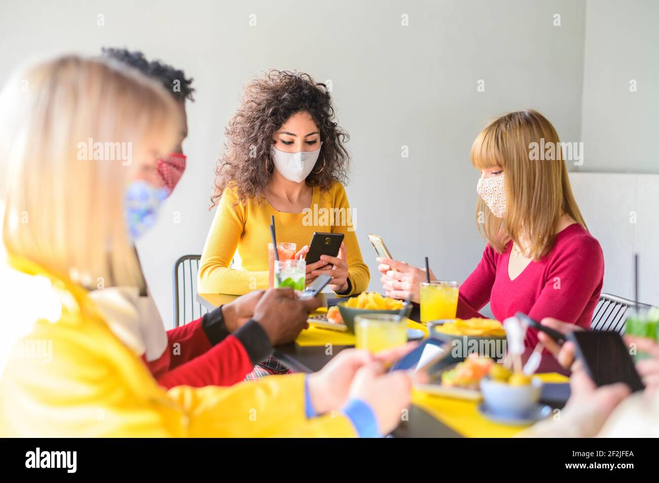 Groupe d'amis utilisant des smartphones mobiles au café-bar - adolescents textant des messages mobiles assis au restaurant - Nouveau concept normal à propos de fr Banque D'Images