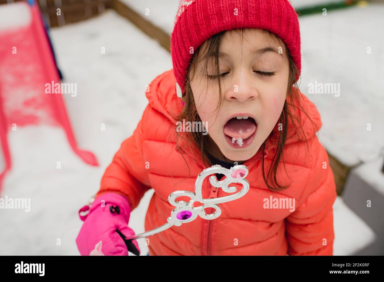 Jeune fille qui goûtant de la neige et tient une baguette magique en hiver jour Banque D'Images