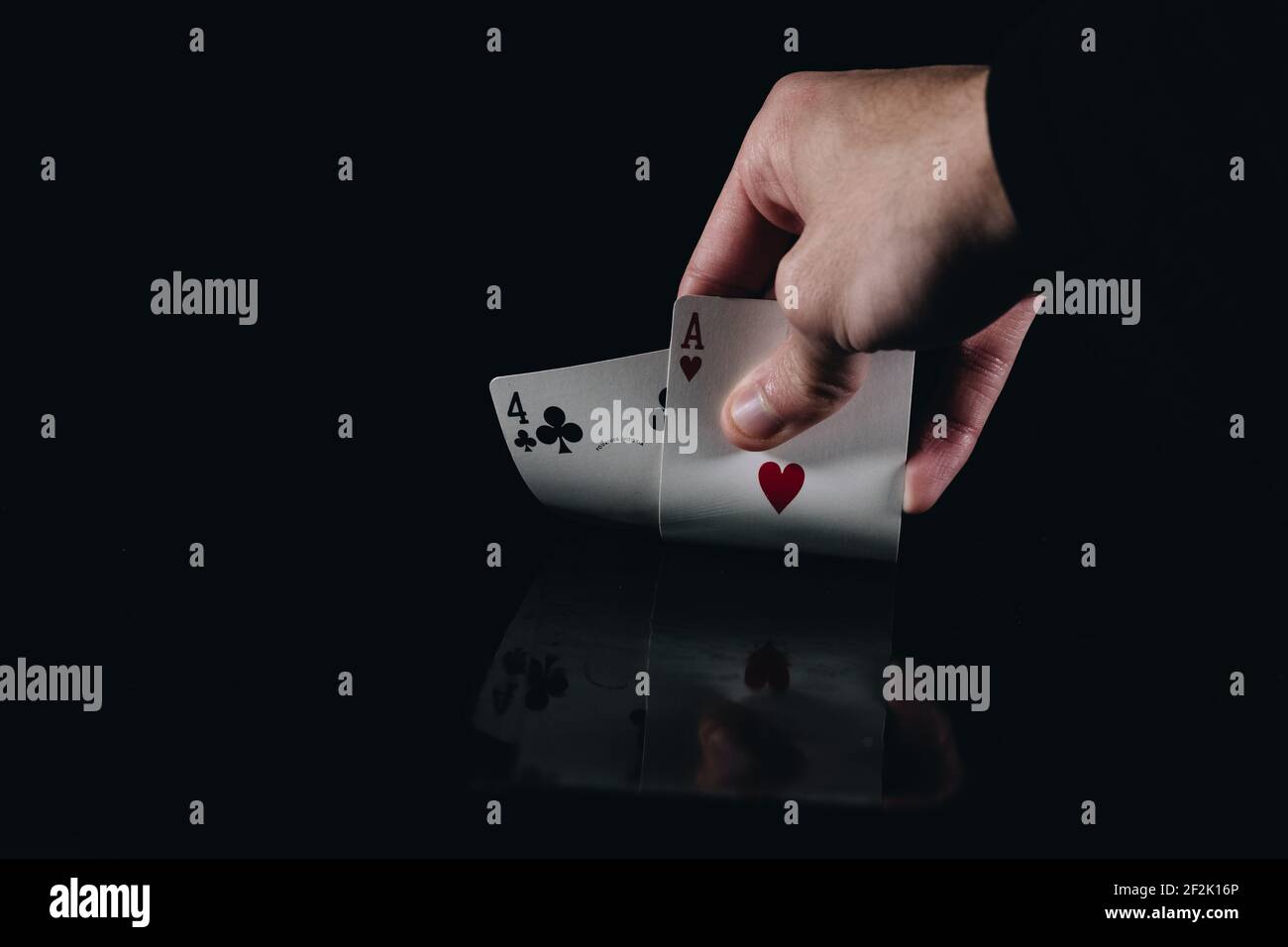 Main mystérieuse tenant deux cartes de poker Banque D'Images