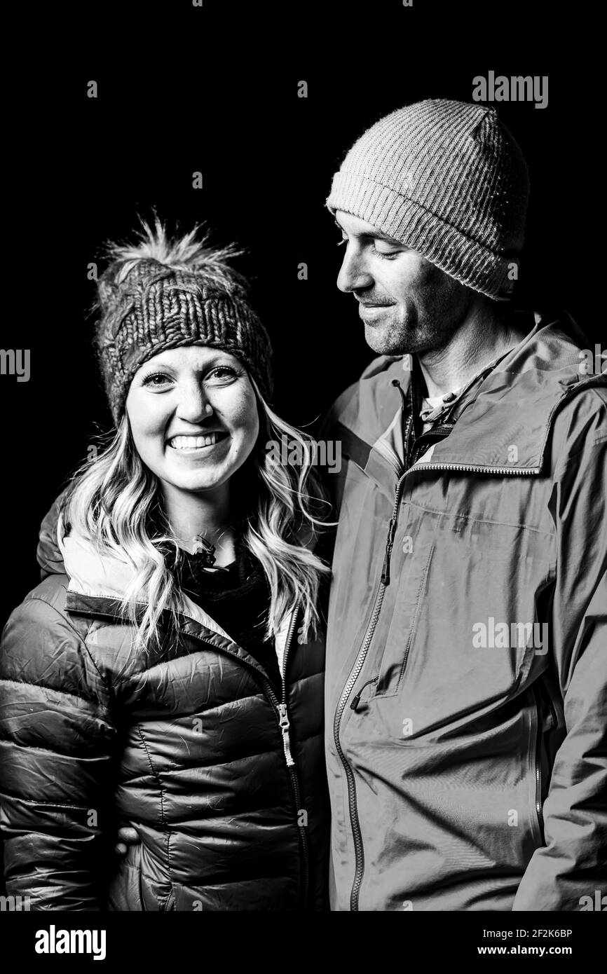 Couple souriant dans des vêtements chauds debout sur fond noir Banque D'Images