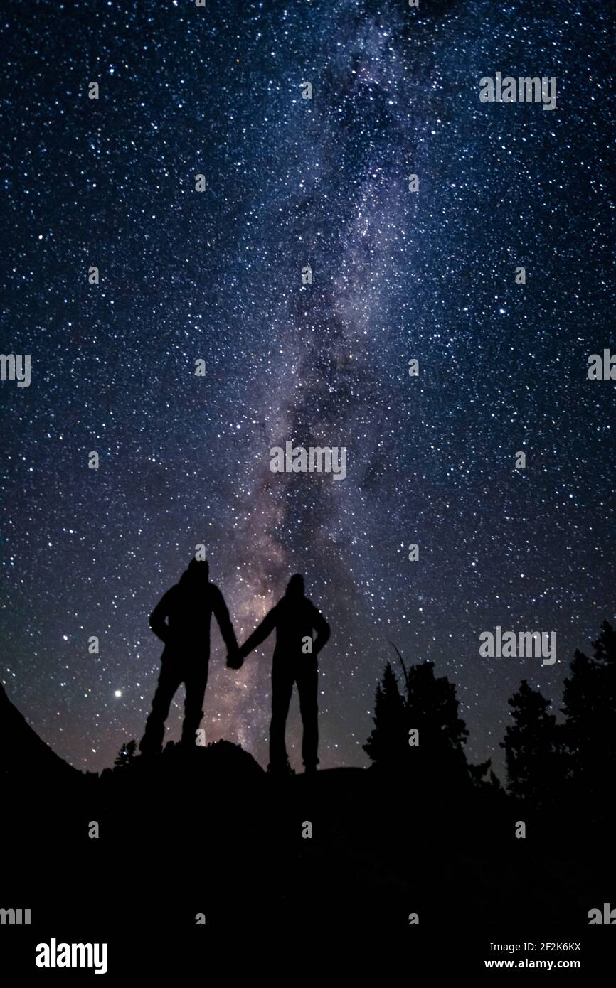 Couple silhouette tenant les mains tout en se tenant contre le beau champ d'étoiles la nuit Banque D'Images