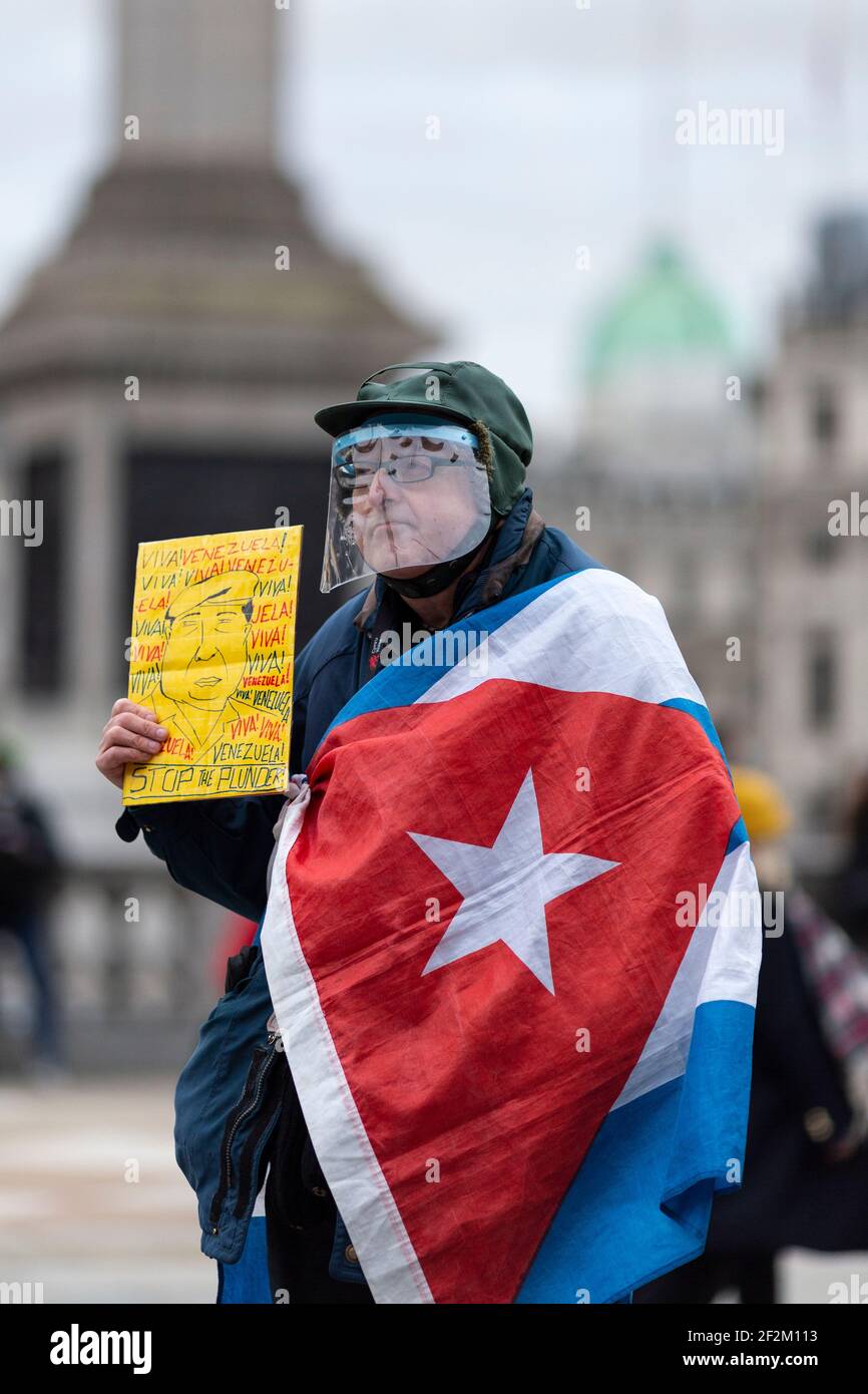Manifestant dans un écran facial avec un écriteau et drapé dans le drapeau cubain, lors d'une manifestation contre l'implication américaine à Cuba, Trafalgar Square, Londres, 12 décembre Banque D'Images