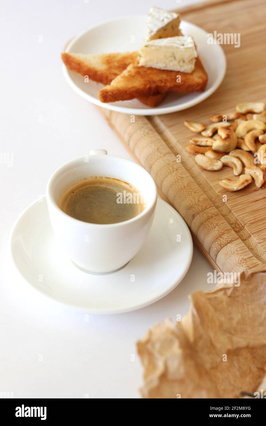 Café du matin servi avec des toasts avec du fromage à la brie et des noix de cajou sur une planche à bois. Petit déjeuner à la maison. Banque D'Images