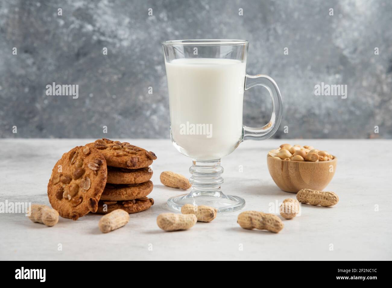 Verre de lait frais et biscuits savoureux avec des arachides arrière-plan en marbre Banque D'Images