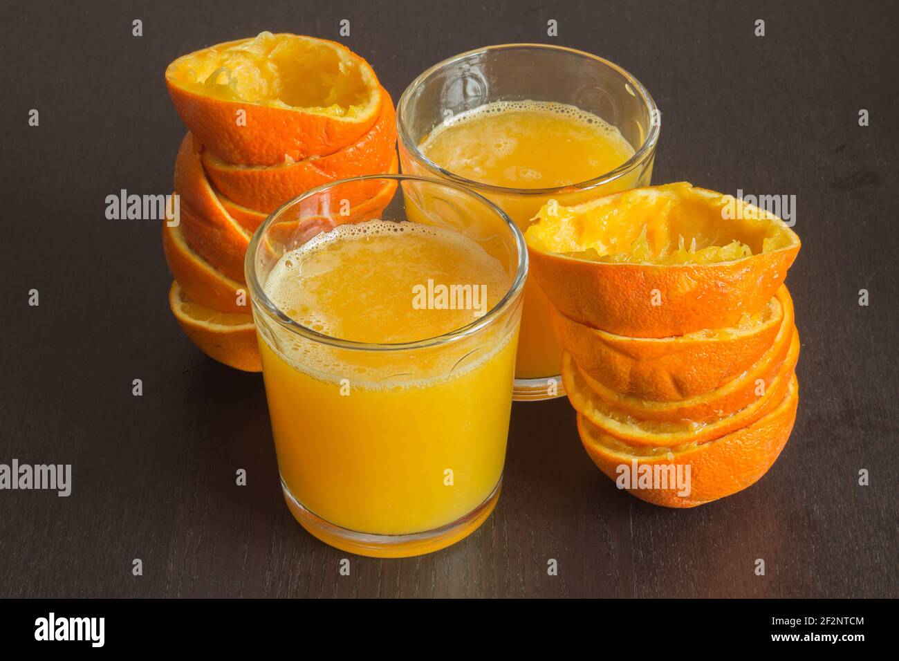 Deux verres de jus d'orange fraîchement pressé avec les fruits à côté d'eux sur une élégante table en bois sombre. Alimentation saine avec des agrumes. Banque D'Images