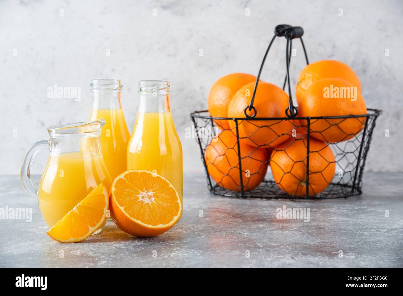 Un panier noir métallique rempli de fruits orange juteux arrière-plan en pierre Banque D'Images