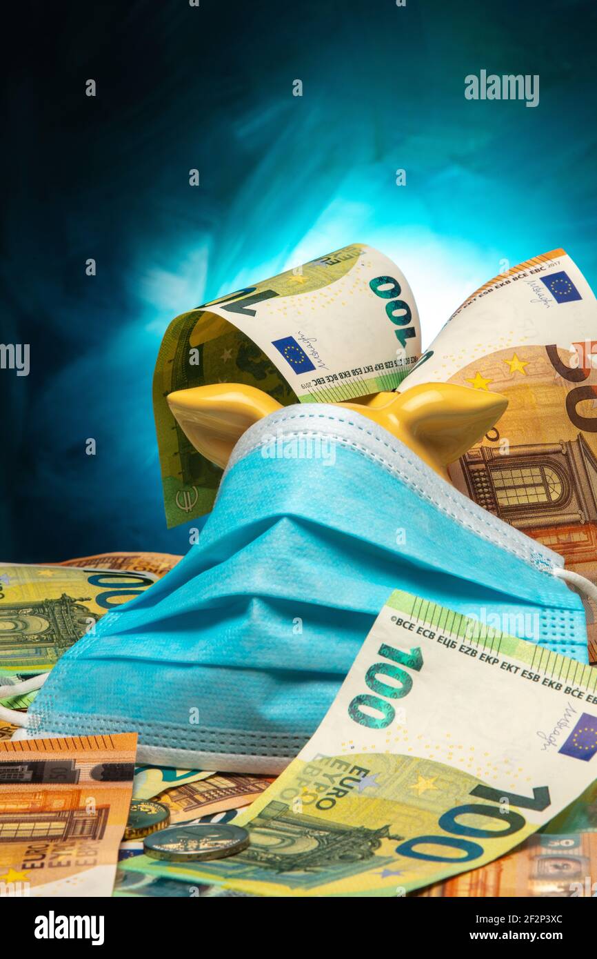 Porcheries avec protection de la bouche et du nez bleus et billets en euros sur fond bleu. Banque D'Images