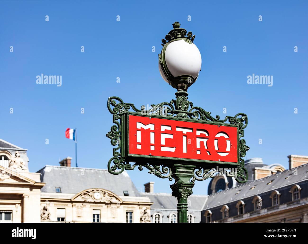 France, Paris, panneau de métro à l'entrée de la station de métro Palais Royal-Musé du Louvre, drapeau d'état en arrière-plan Banque D'Images