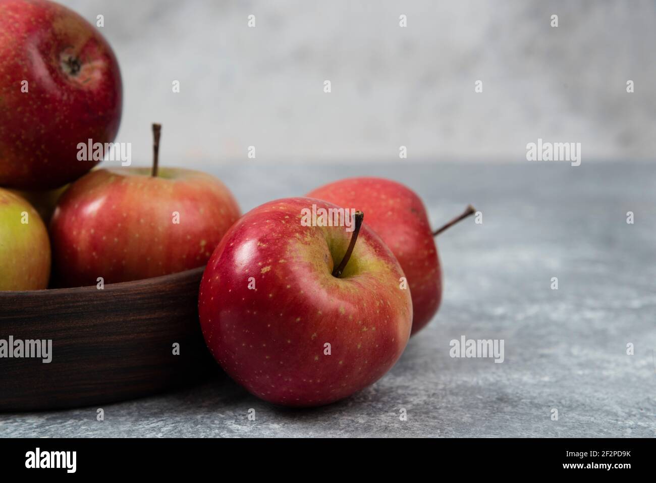 Bol en bois de pommes fraîches et savoureuses sur une surface en marbre Banque D'Images