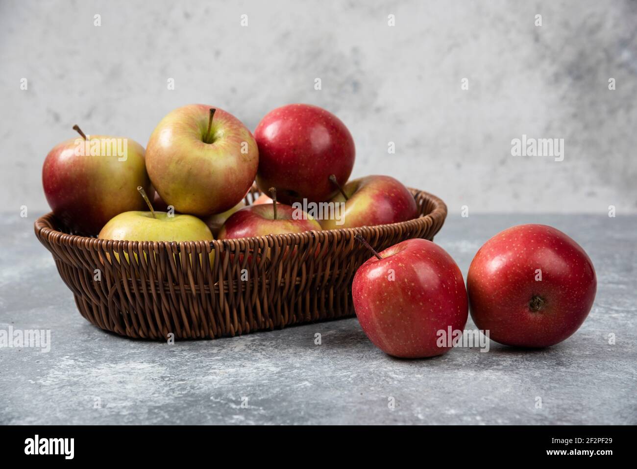 Panier en osier de pommes juteuses rouges sur une surface en marbre Banque D'Images