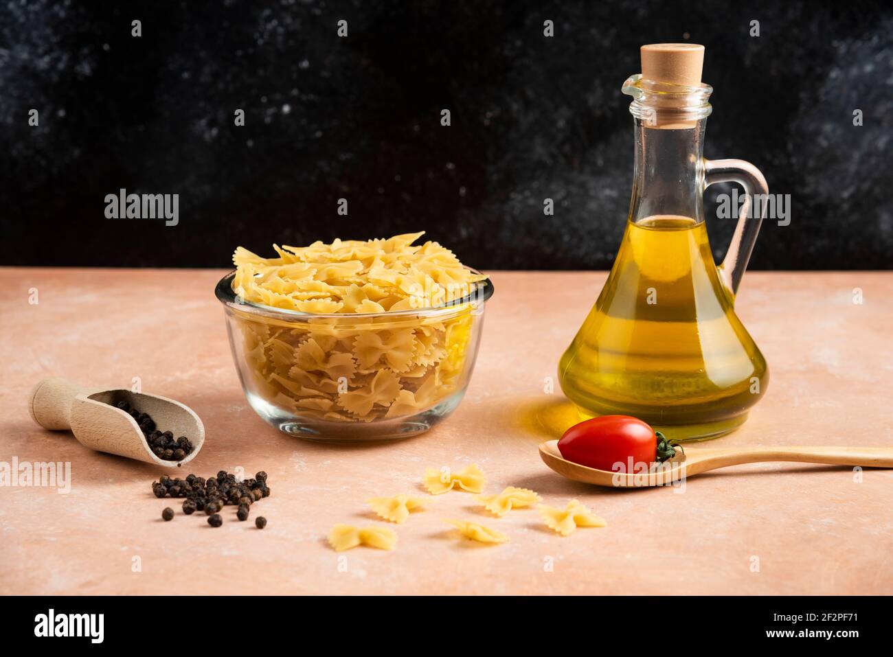 Bol de pâtes crues et d'huile d'olive sur une table orange Banque D'Images