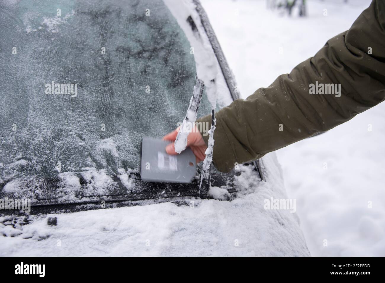 Allemagne, Saxe-Anhalt, Magdebourg, un homme égratigne la fenêtre gelée de sa voiture libre. Banque D'Images