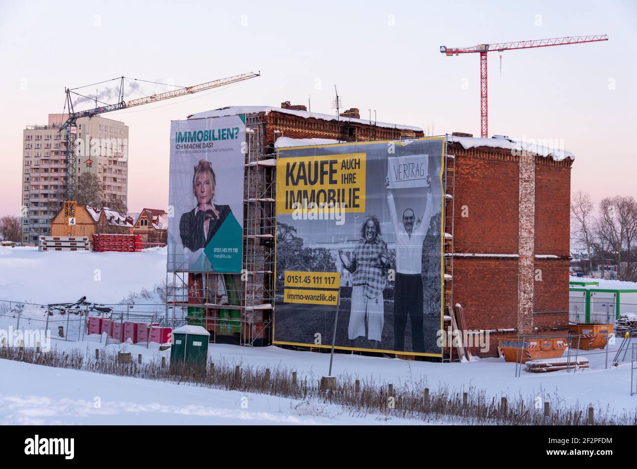 Allemagne, Saxe-Anhalt, Magdeburg, publicité pour des achats immobiliers dans une maison de démolition. Derrière elle se trouvent des grues de construction et une tour haute. Banque D'Images