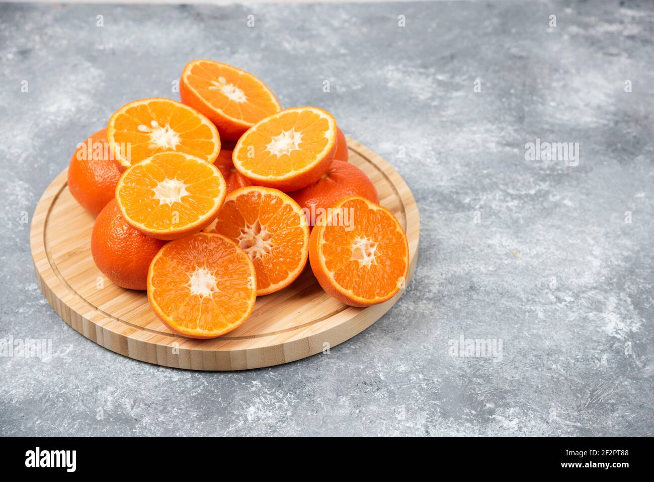 Émincé de fruits frais à l'orange dans une assiette en bois Banque D'Images