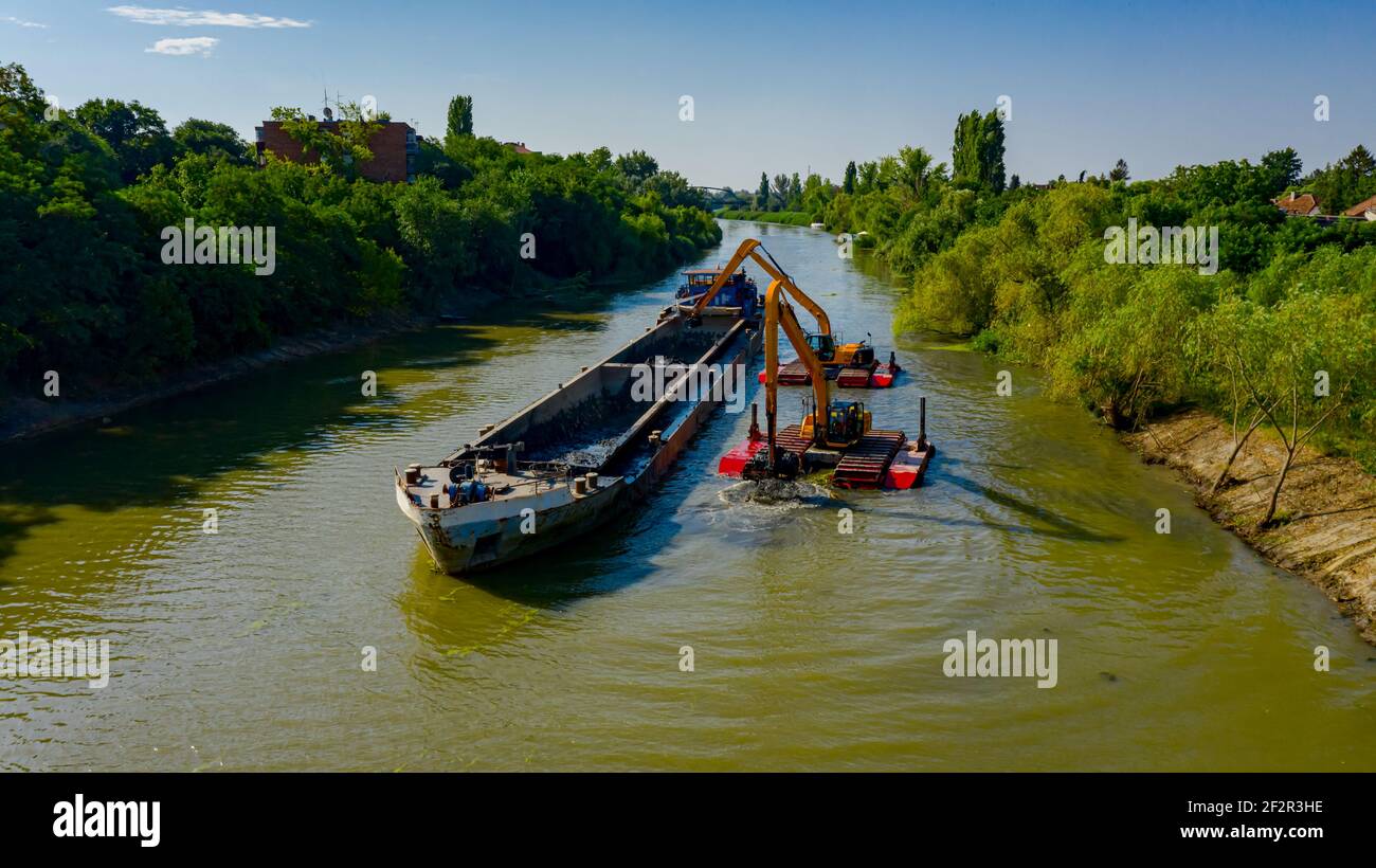 Au-dessus de la vue sur deux excavateurs drague comme ils dragage, travaillant sur la rivière, canal, l'approfondissement et l'enlèvement des sédiments, la boue du lit de la rivière dans une eau polluée Banque D'Images