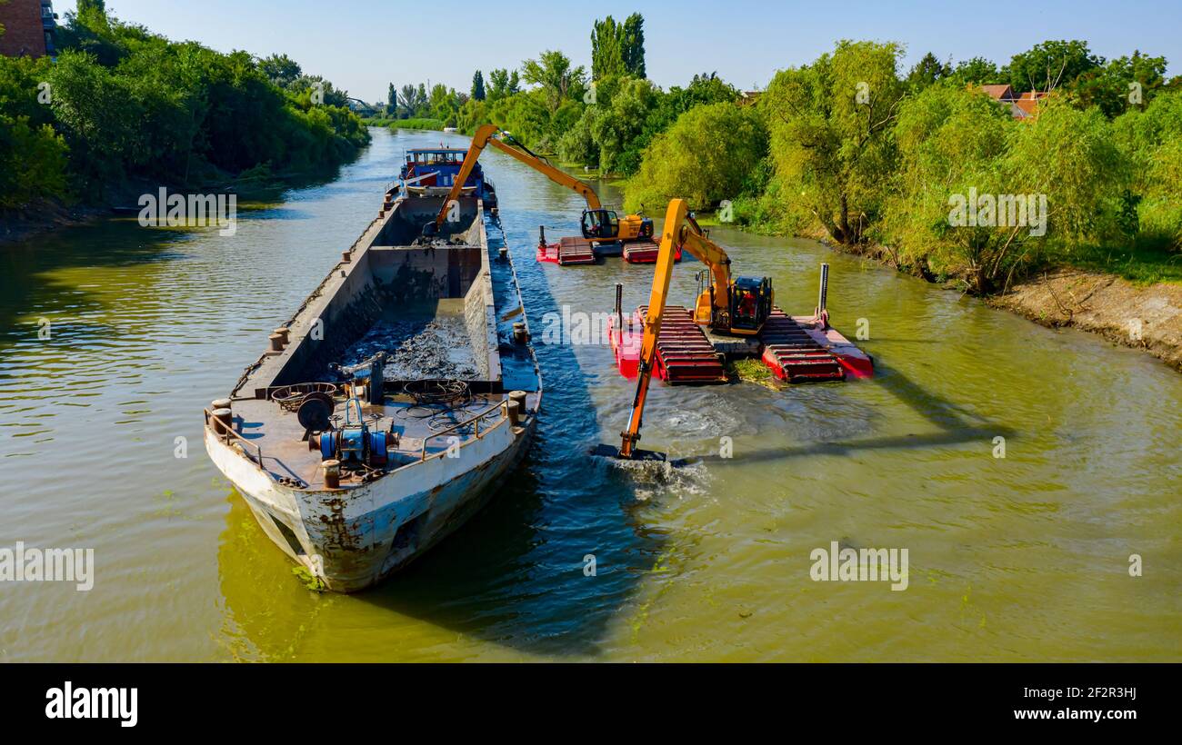 Au-dessus de la vue sur deux excavateurs drague comme ils dragage, travaillant sur la rivière, canal, l'approfondissement et l'enlèvement des sédiments, la boue du lit de la rivière dans une eau polluée Banque D'Images