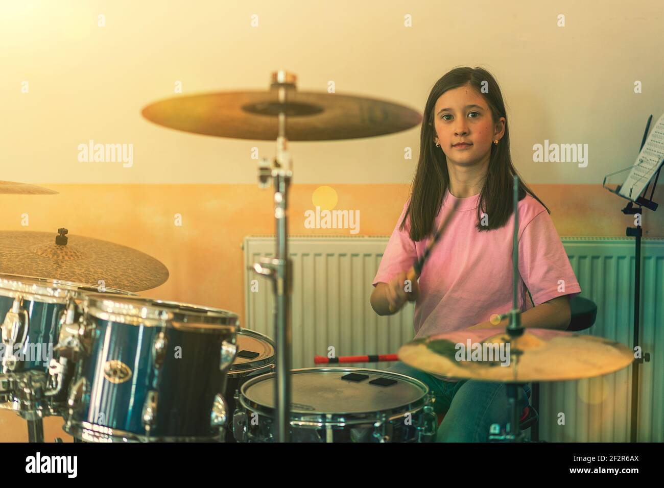 Bonne fille en musicothérapie en jouant au kit de batterie dans la salle de  musique. Belle jeune fille batteur avec des pilons jouant des tambours et  des cymbales. Batteur féminin Photo Stock -