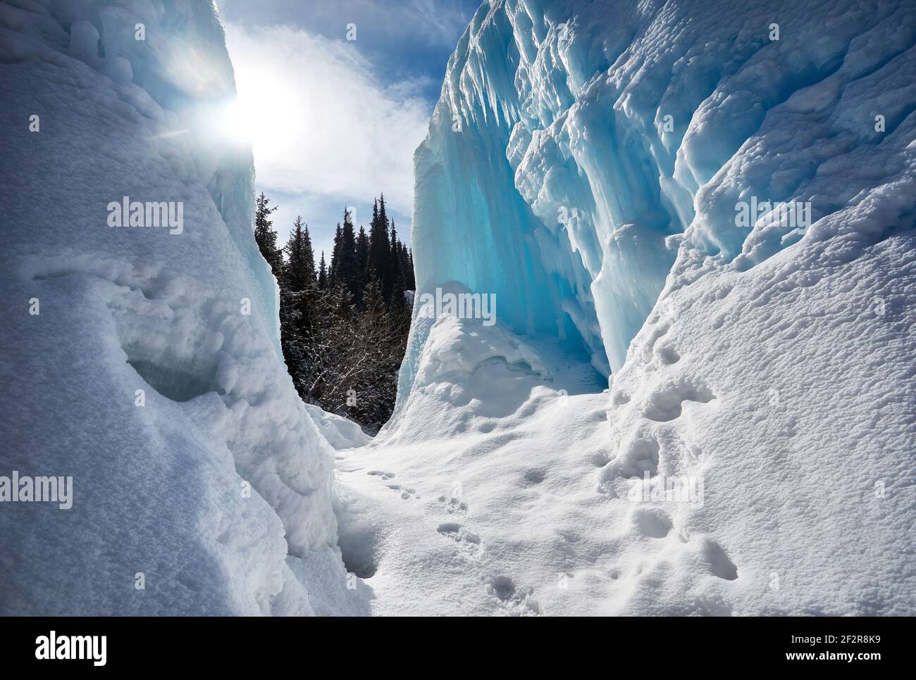 Chute d'eau de montagne gelée avec des glaçons contre le ciel bleu et la forêt en arrière-plan Banque D'Images