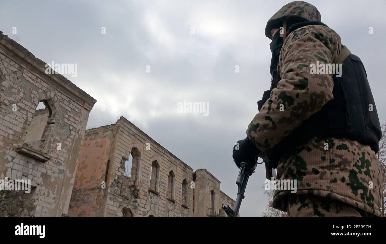 AGDAM, AZERBAÏDJAN - DÉCEMBRE 14 : un soldat azerbaïdjanais s'est intéressé à un bâtiment en ruines dans la ville d'Agdam qui a été détruit par les forces arméniennes pendant la première guerre du Haut-Karabakh le 14 décembre 2020 à Agdam, en Azerbaïdjan. La ville et son district avoisinant ont été retournés sous contrôle azerbaïdjanais dans le cadre d'un accord qui a mis fin à la guerre du Haut-Karabakh de 2020. Banque D'Images