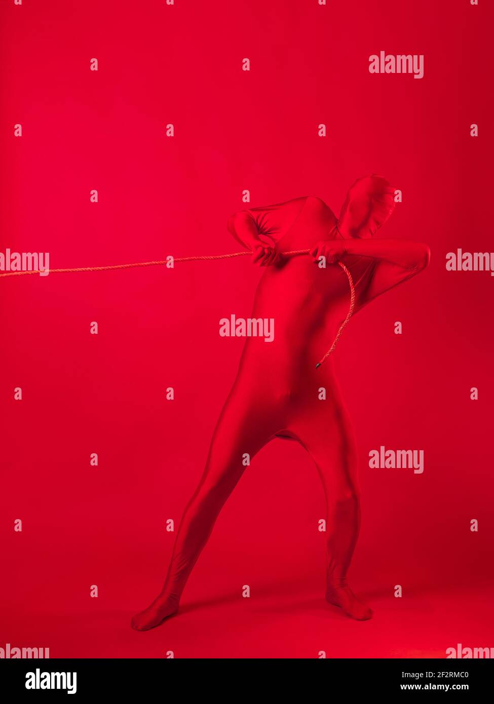 Un homme rouge anxieux dans un léopard rouge, traînant un lourd fardeau, tirant une lourde charge avec une corde. Le concept de stress et de surmenage au travail. Banque D'Images Un homme rouge anxieux dans un léopard rouge, traînant un lourd fardeau, tirant une lourde charge avec une corde. Le concept de stress et de surmenage au travail. Banque D'Images