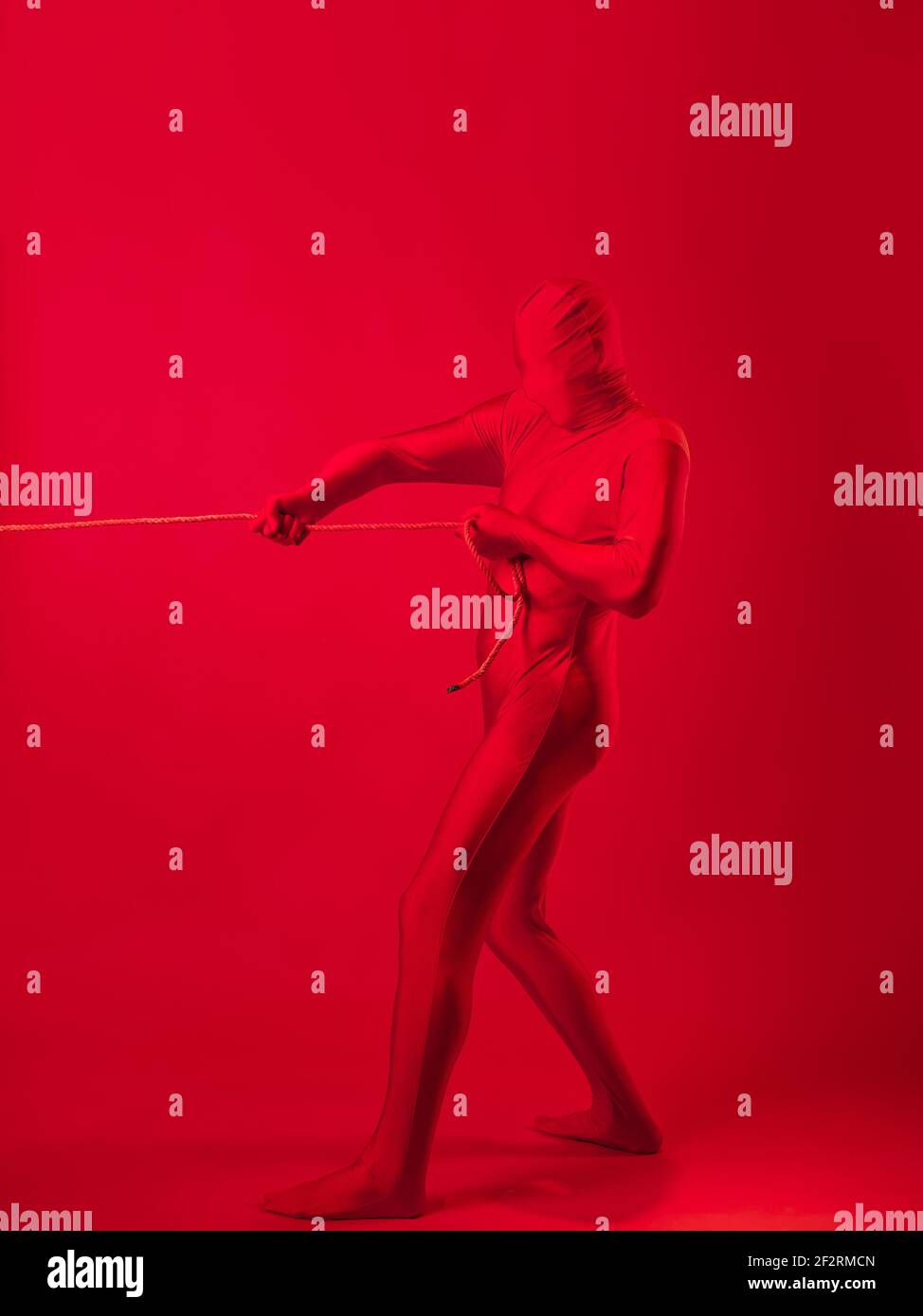 Un homme rouge anxieux dans un léopard rouge, traînant un lourd fardeau, tirant une lourde charge avec une corde. Le concept de stress et de surmenage au travail. Banque D'Images Un homme rouge anxieux dans un léopard rouge, traînant un lourd fardeau, tirant une lourde charge avec une corde. Le concept de stress et de surmenage au travail. Banque D'Images