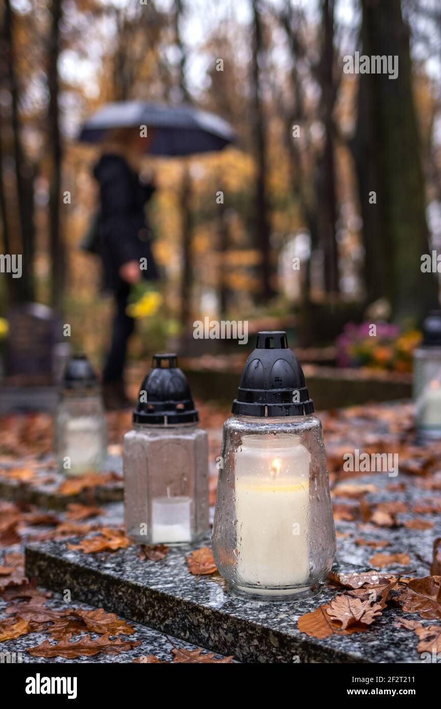 Lanterne de bougie tombe à la tombe et deuil de la femme avec un parapluie  dans le cimetière. Se souvenir des morts Photo Stock - Alamy