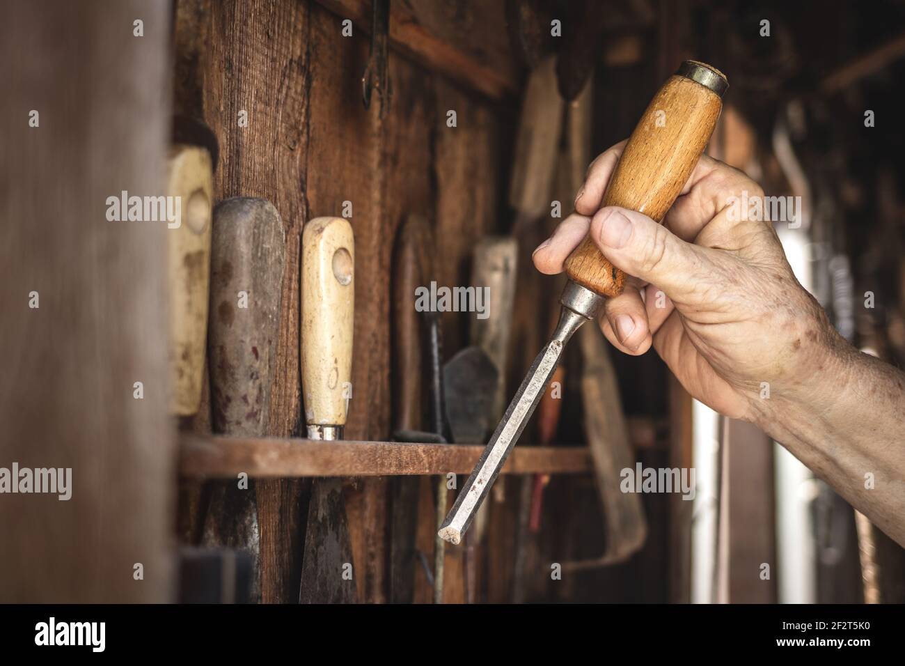 Artisan tenant le burin dans la vieille main. Outils de menuiserie en atelier. Banque D'Images