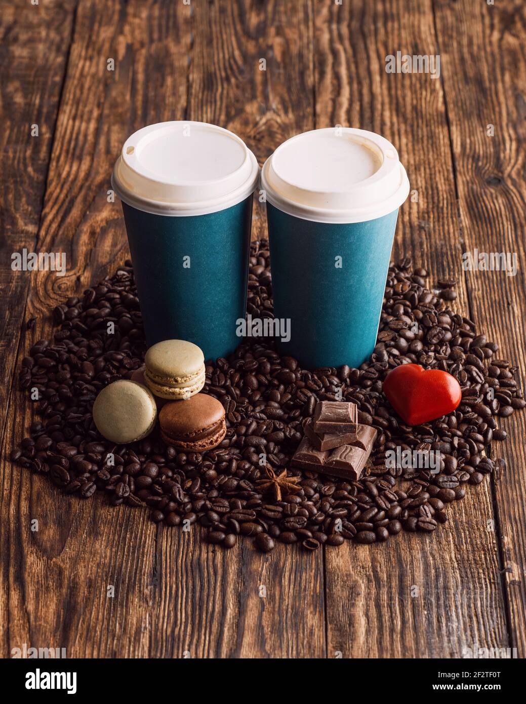 deux tasses en papier de café, macarons, haricots, coeur sur fond de bois Banque D'Images
